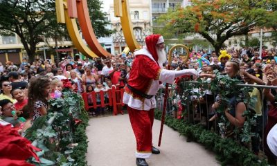 Papai Noel em cima de um palco cercado por crianças