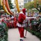 Papai Noel em cima de um palco cercado por crianças