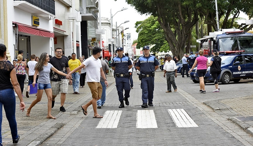 pessoas atravessando na faixa de pedestre no Centro de Jundiaí, com guardas municipais ao lado.