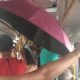 Foto de ônibus lotado com passeiros embaixo de um guarda-chuva aberto