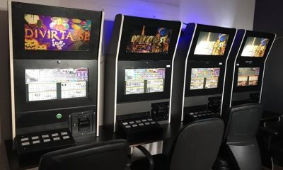 Quatro máquinas caça-níquel em fileiras, com telas de jogos abertas.