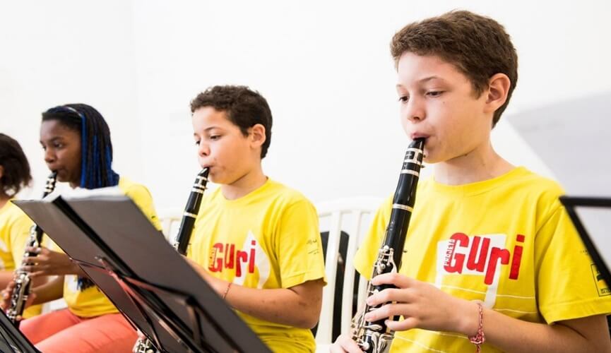 Meninos de, aparentemente, 9 anos, tocando flautas com uniformes amarelos