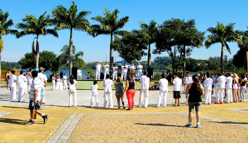 Roda de capoeira no parque da cidade, com participação de pessoas com trajes de ginásticas
