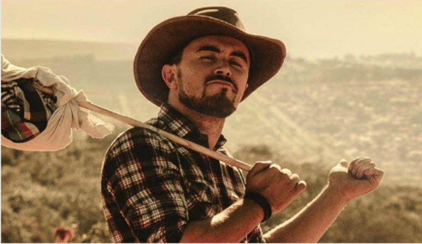 Foto de homem vestido de cowboy com uma trouxa de roupa em uma vara.