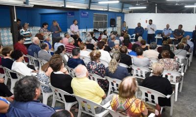 Luiz Fernando Machado ao lado de autoridades falando para público em salão fechado