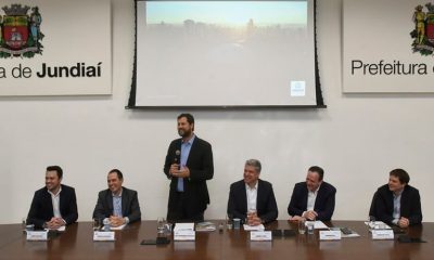 Prefeito Luiz Fernando Machado apresentando estudo ao lado de outras autoridades jundiaienses em sala com telão.