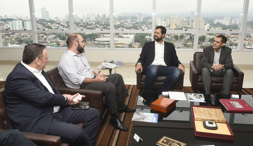 Reunião no gabinete do prefeito de Jundiaí, comdois empresários sentados à esquerda e prefeito e gestor sentados à direita, com cidade de jundiaí ao fundo pela janela