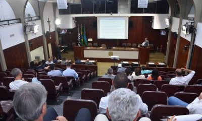 pÚBLICO SENTADO EM CADEIRAS DE CÂMARA MUNICIPAL ACOMPANHANDO AUDIÊNCIA PÚBLICA COM HOMENS SENTADOS À FRENTE