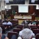 pÚBLICO SENTADO EM CADEIRAS DE CÂMARA MUNICIPAL ACOMPANHANDO AUDIÊNCIA PÚBLICA COM HOMENS SENTADOS À FRENTE