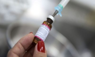 mão de mulher segurando dose de vacina com fundo desfocado