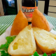 Coxinha de queijo cortada ao meio, com garrafa de Turbaína atrás.