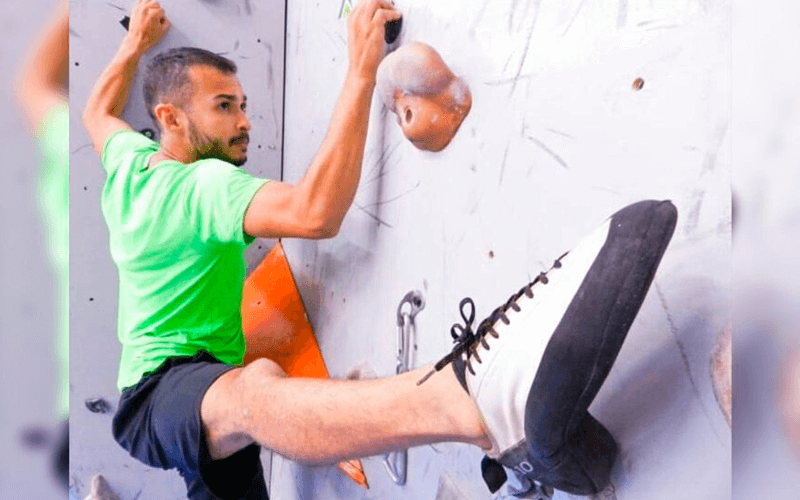 Homem tentando escalar parede com obstáculos