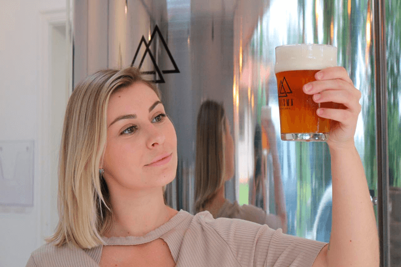 Aline segurando admirando um copo de cerveja Prisma