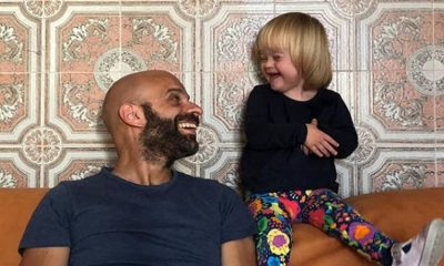 Homem sorrindo para criança loira em sofá