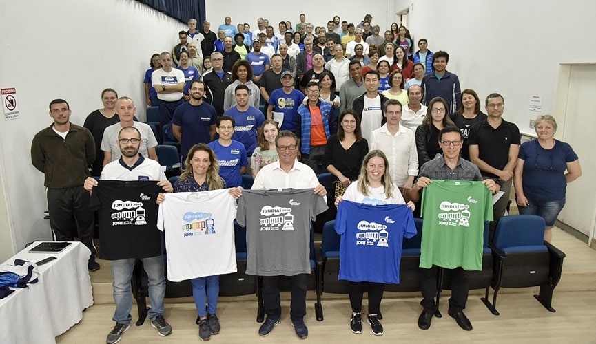 Pessoas segurando camisetas esportivas nas cores: branca, preta, cinza, azul e verde