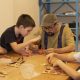 Homem ensinando crianças a fazer artesanato