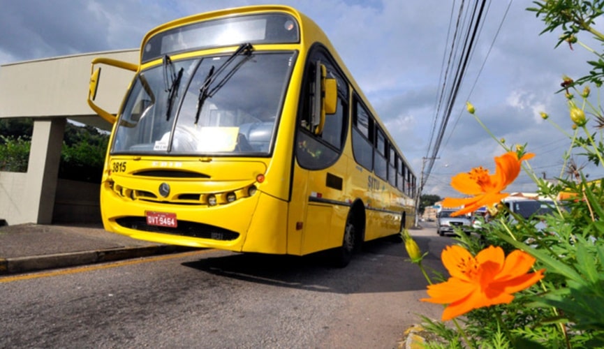 ônibus amarelo de Jundiaí em rua com flores laranjas na calçada