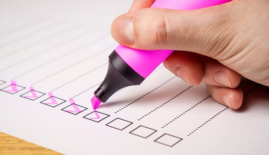 Pessoa marcando lista com uma caneta marca-texto rosa