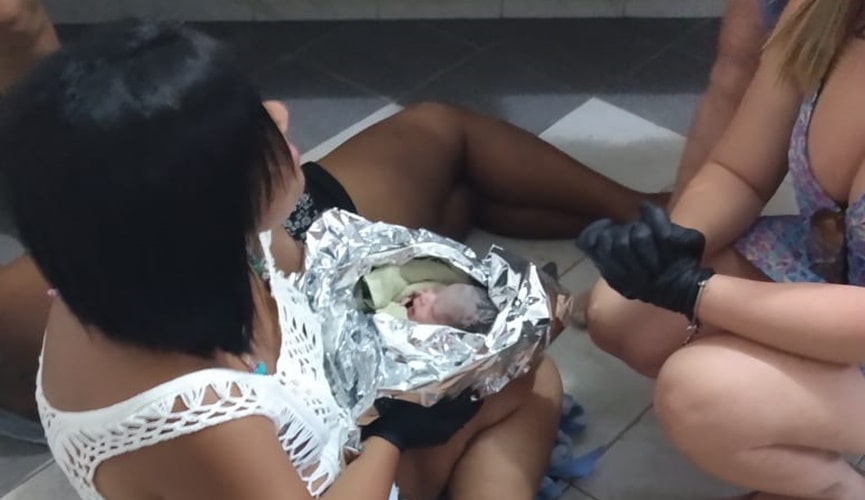Bebê recém-nascido em manta térmica no colo de Renata