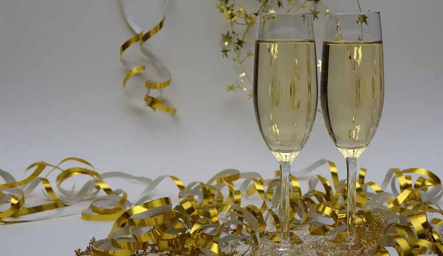 dois copos de champagne com funco brnco e pedaços de fitas douradas