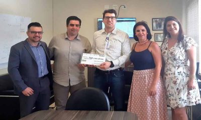 Superintendente do Hospital São Vicente ao meio recebendo cheque simbólico das mãos do presidente da ACE Jundiaíi, ao seu lado esquerdo. também há um outro homem e duas outras mulheres na foto, da diretoria da ACE