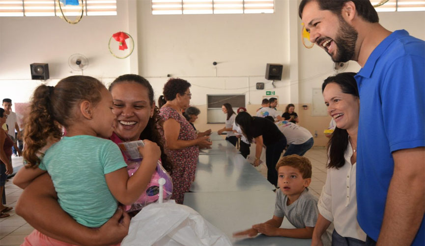 prefeito luiz fernando machado e sua esposa, a primeira-dama vanessa machado, entregam brinquedos para mãe com filha no coolo