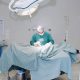cirurgião em centro cirúrgico com paciente em maca coberto por lençol