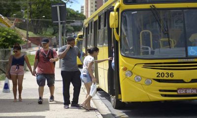 ônibus amarelo de jundiaí parado em avenida enquanto pessoas que estão na calçada paradas no ponto de ônibus sobem para dentro dele