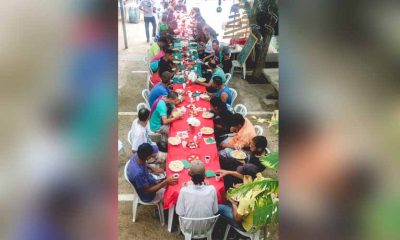 moradores de rua em mesa com toalha vermelha almoçando