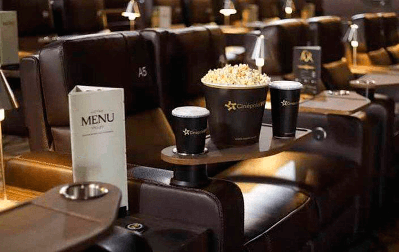 Sala de cinema VIP vazia com menu de restaurante e balde de pipoca