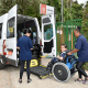 Criança de cadeira de rodas deixa van adaptada com auxílio de duas funcionárias