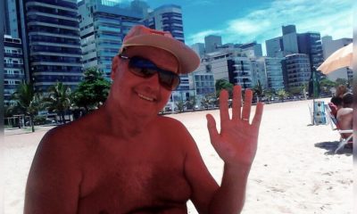 professor Zé Dias na praia acena para a fotografia