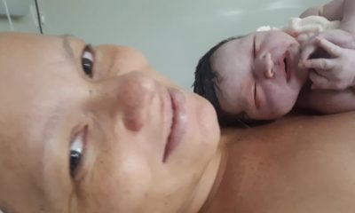 Mãe, durante pós-parto, com bebê recém-nascida nos braços