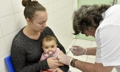 Mãe segurando criança que está sendo vacinada