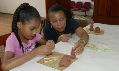 Criança e mulher negra fazendo escultura de argila