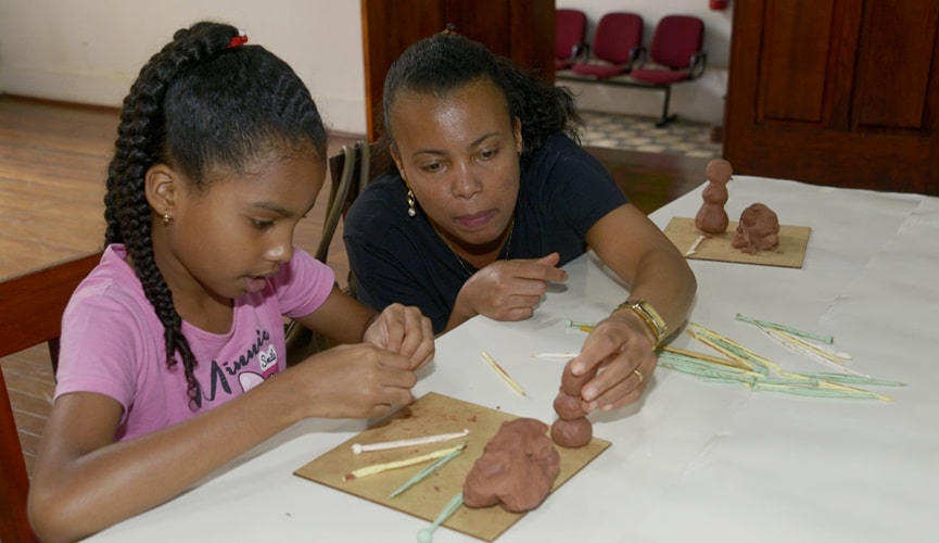 Criança e mulher negra fazendo escultura de argila