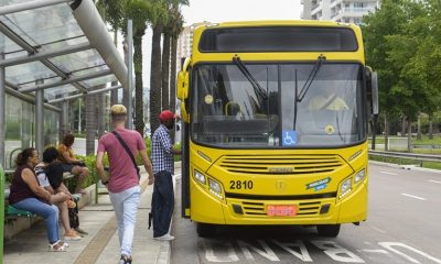 Pessoas entrando em ônibus amarelo