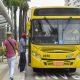 Pessoas entrando em ônibus amarelo