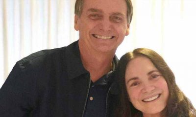 O presidente Jair Bolsonaro posa ao lado da atriz Regina Duarte. Ambos sorriem na foto.