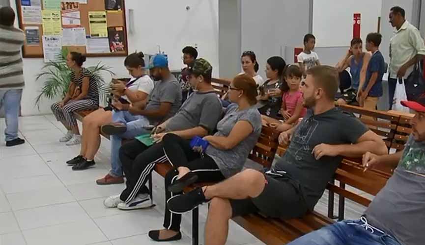 pessoas sentadas em bancos de madeira em cartório aguardando atendimento