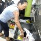 mulher depositando alimentos em caixa em frente ao parque da uva