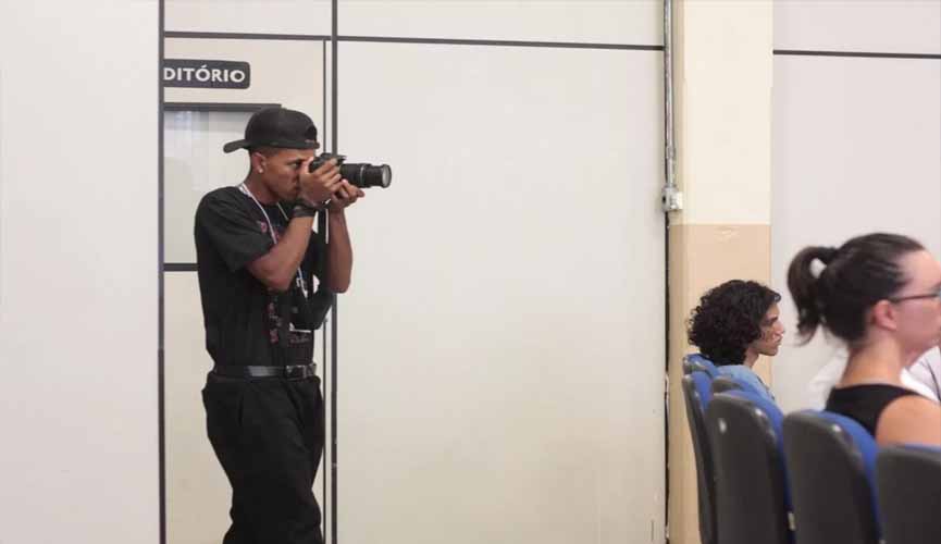 jovem negro segura câmera profissional enquanto tira foro em sala
