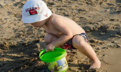 criança na praia brincando na areia com baldinho
