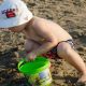 criança na praia brincando na areia com baldinho