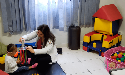 Profissional em sala de recursos auxilia criança com deficiência visual