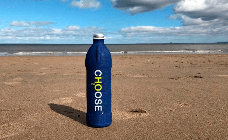 Choose Water de embalagem azul em uma areia de praia