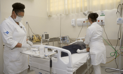 Enfermeiras realizando exame em paciente que está deitado em cama hospitalar