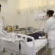 Enfermeiras realizando exame em paciente que está deitado em cama hospitalar