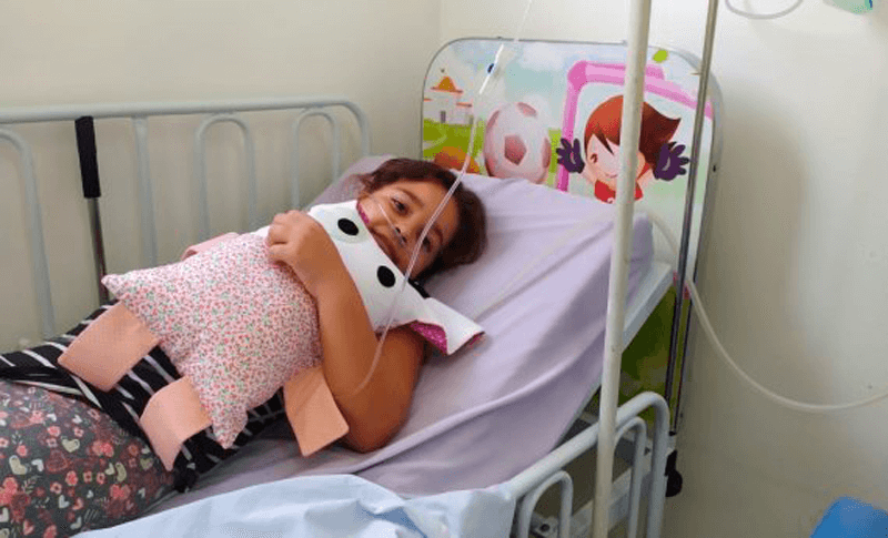 Criança abraçada com naninha em casa hospitalar