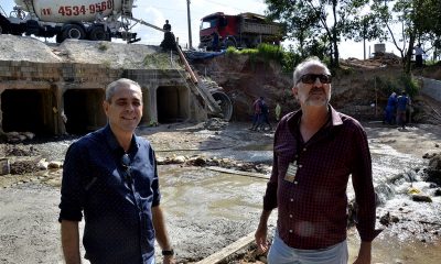 dois homens um do lado do outro observando uma obra de construção de um túnel